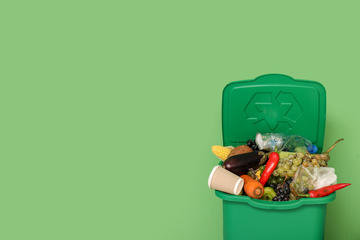 A green bin is filled with vegetable peelings and waste.