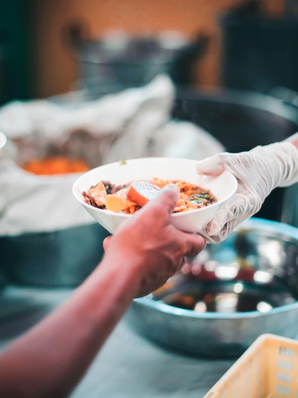 One arm passes another reaching arm a bowl of vegetables