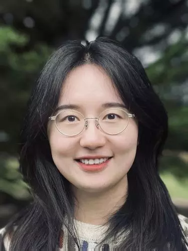A woman with long dark hair smiles at the camera. 