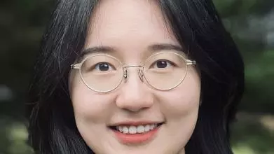 A woman with long dark hair smiles at the camera. 